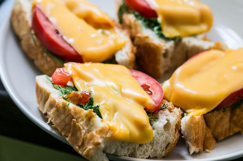 白色瓷盘里的放着西红柿奶酪的三明治