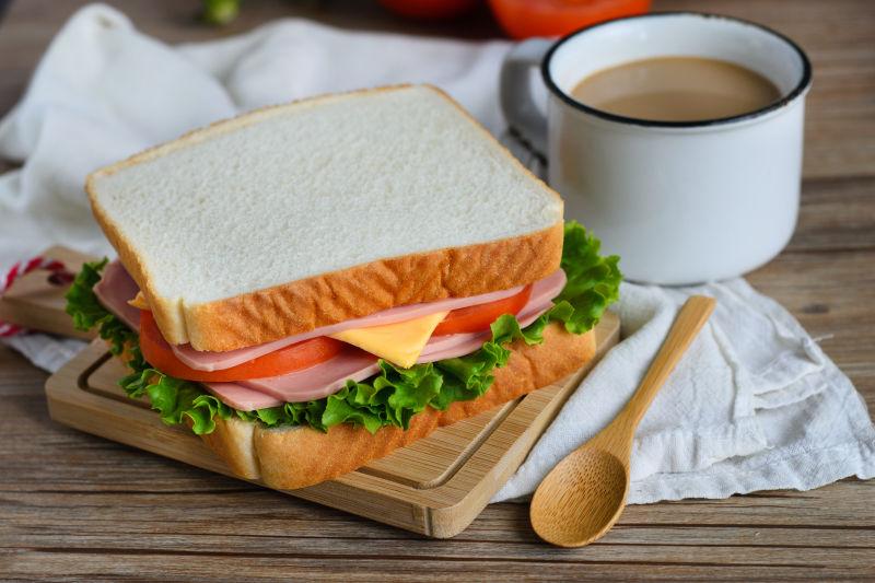 放在木质砧板上的夹着西红柿蔬菜的美味的三明治