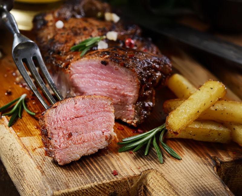 新鲜美味的烤迷迭香牛排加迷迭香在木制背景下