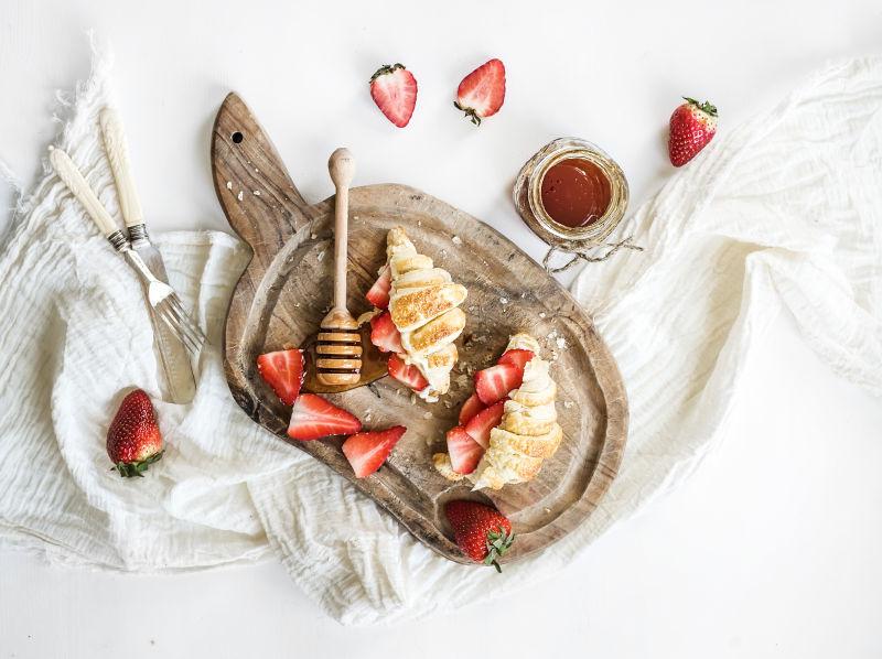 新鲜烘焙羊角面包与马斯卡彭和蜂蜜在白色的背景