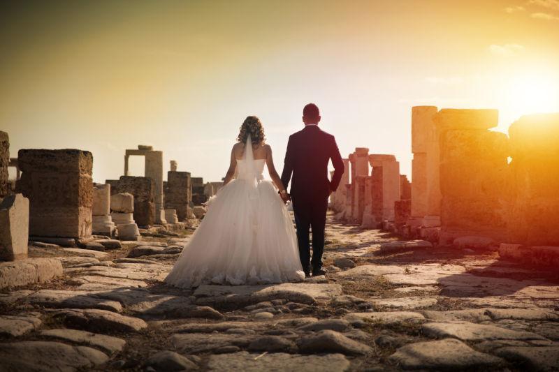落日下的古城墙上的一对结婚新人