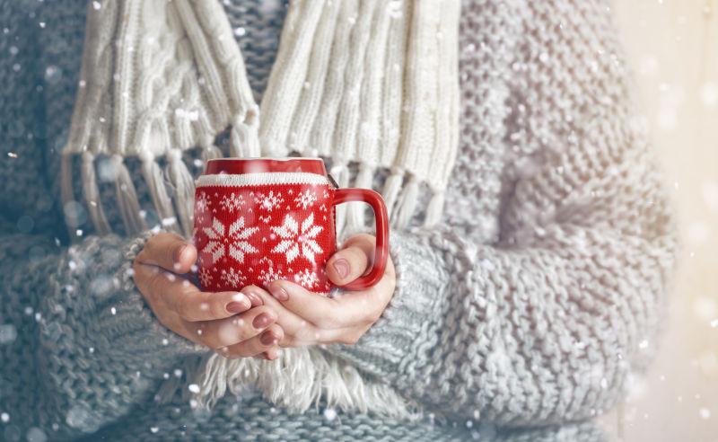 女孩穿着针织毛衣手里拿着一个杯子