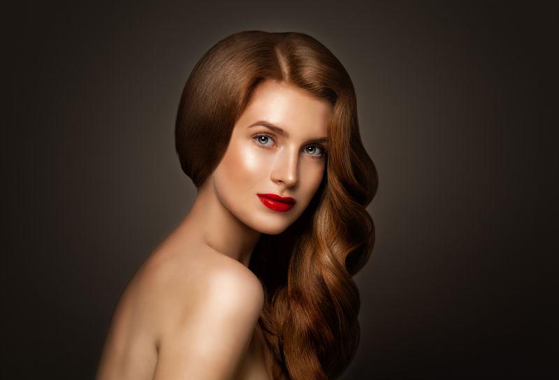 完美的红色波浪状的头发的迷人的女人