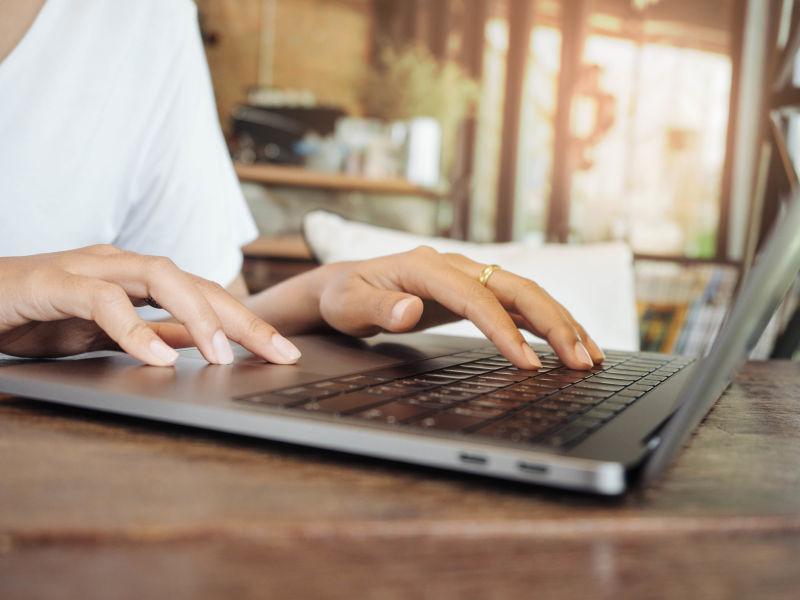 木桌边使用笔记本电脑的男人