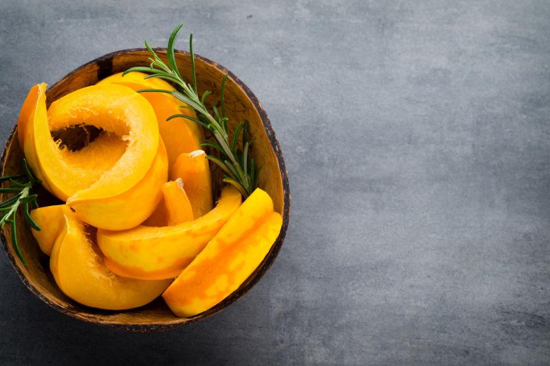 灰色背景下木制盘子里的南瓜切片