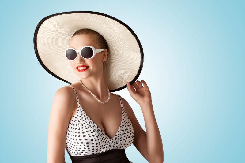 一位漂亮时尚的性感女人戴着太阳帽与太阳眼镜