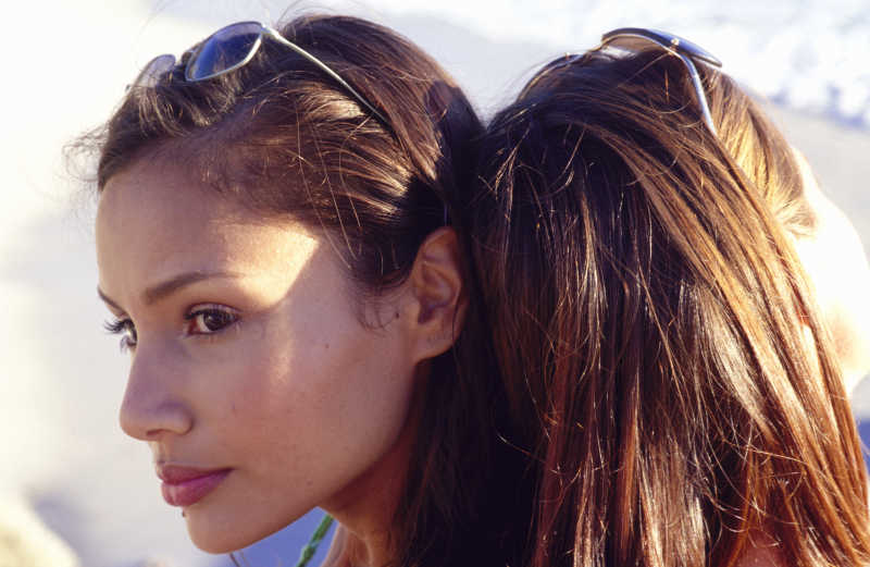 海滩上背靠在一起享受度假时光的年轻女子