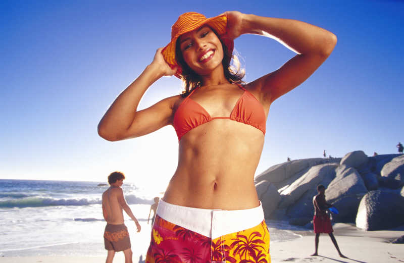 假日海滩双手抱头微笑的比基尼女孩