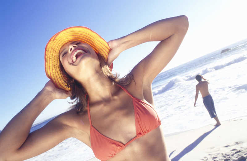海滩上双手抱头开心大笑的比基尼女孩