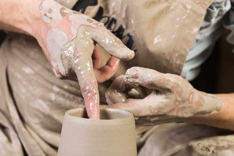 陶瓷艺术概念—人的手上的最高视角与陶工轮子和生粘土一起工作特写