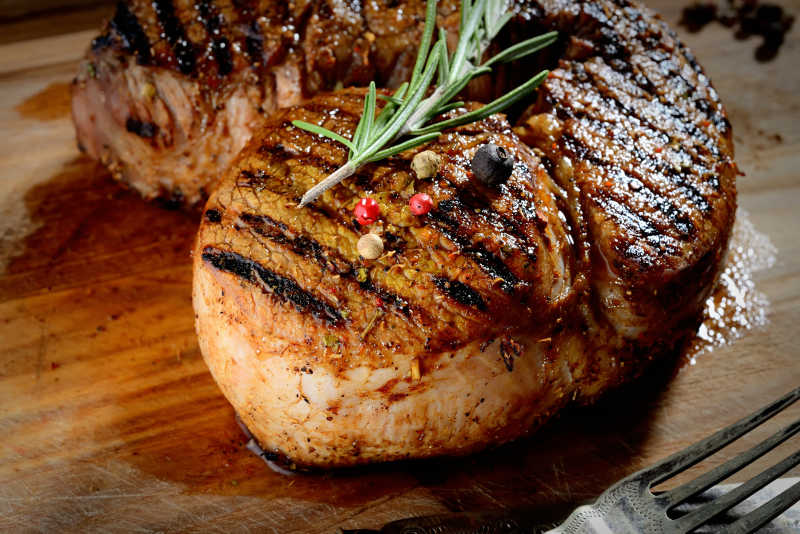 木制背景上的牛排和迷迭香