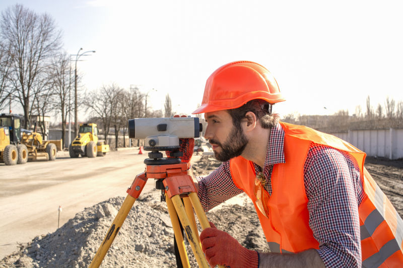 戴頭盔在建築工地工作的男性測量工程師