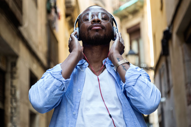 英俊的年轻人用数码平板电脑听音乐