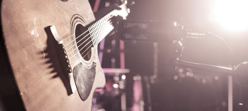 录音室的麦克风录下了一个原声吉他特写镜头彩灯的美丽模糊背景