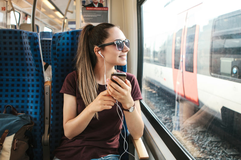 一个年轻女孩在火车上旅行时听音乐或播客