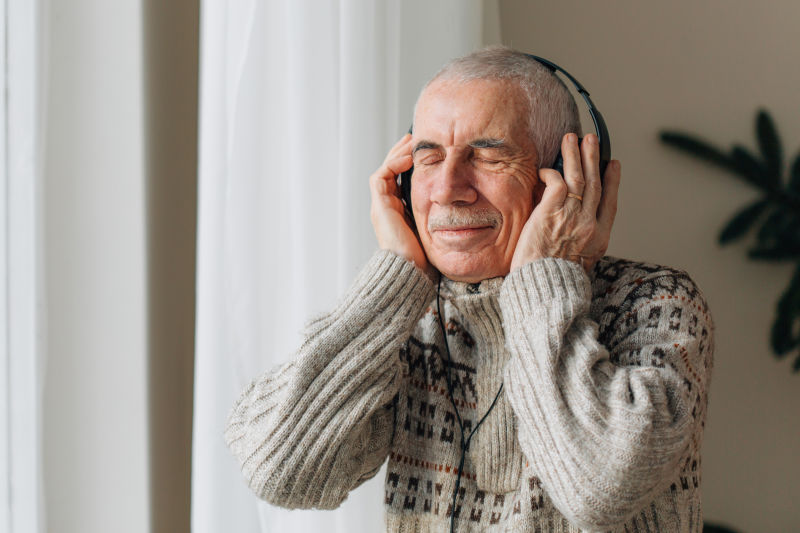 英俊的老人戴着耳机听音乐