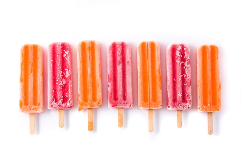 橙色和草莓冰棍白色背景俯视图