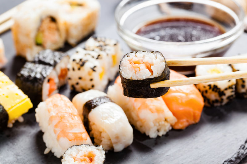 各种寿司和面包卷的黑石板托盘