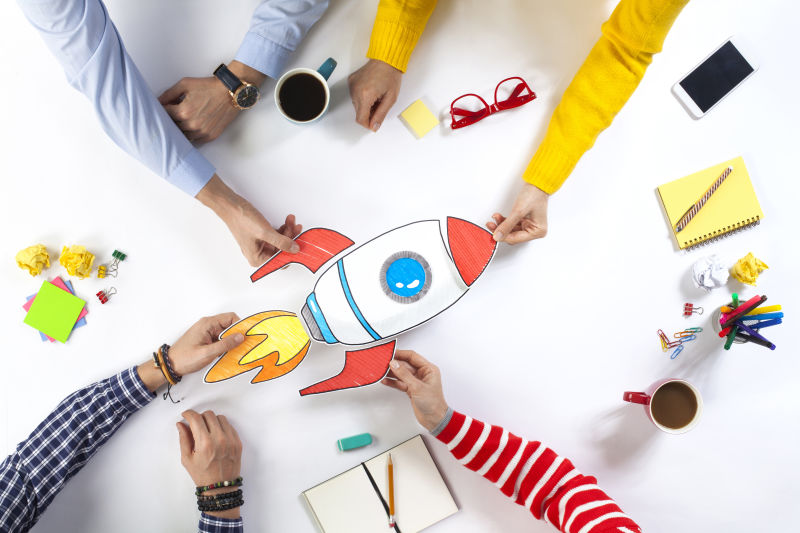 创意团队坐在桌旁-与创业火箭一起