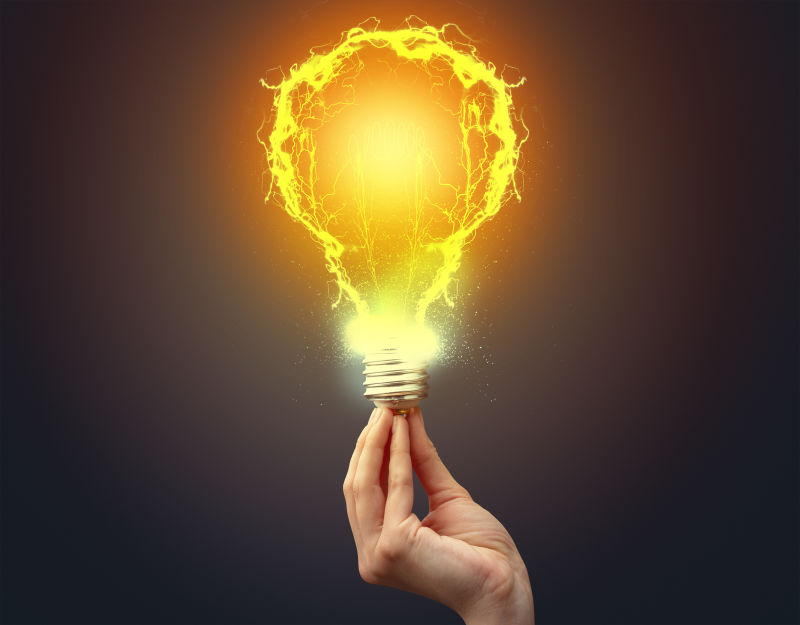 在黑暗的背景下手持闪亮的灯泡-新概念