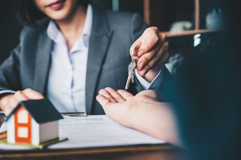房地产经纪人将房子钥匙交给妇女并在办公室签署协议