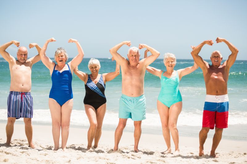 老年人在海滩上摆着肌肉的姿势