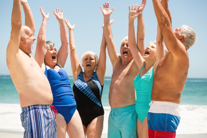 在海滩上举起手的老年人