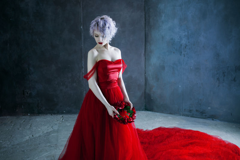 穿红衣服的年轻漂亮的女人手里拿着一个玫瑰花圈纹理背景