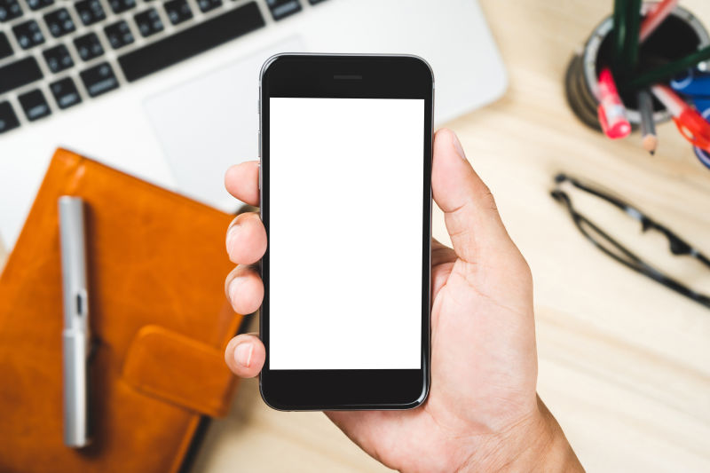 手持移动智能手机独立的白色屏幕-用于笔记本电脑笔记本电脑和眼镜背景上的实体模型设计