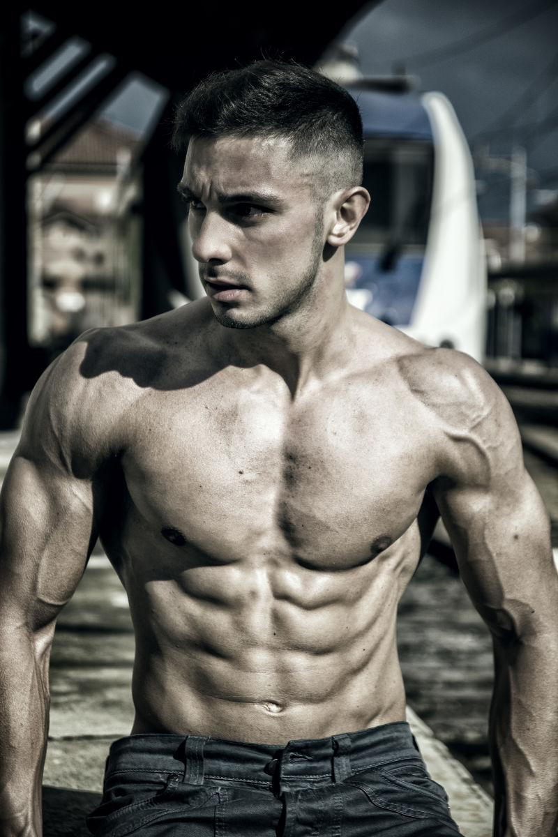 年轻的赤膊男子性感的身躯俯视火车站的照片