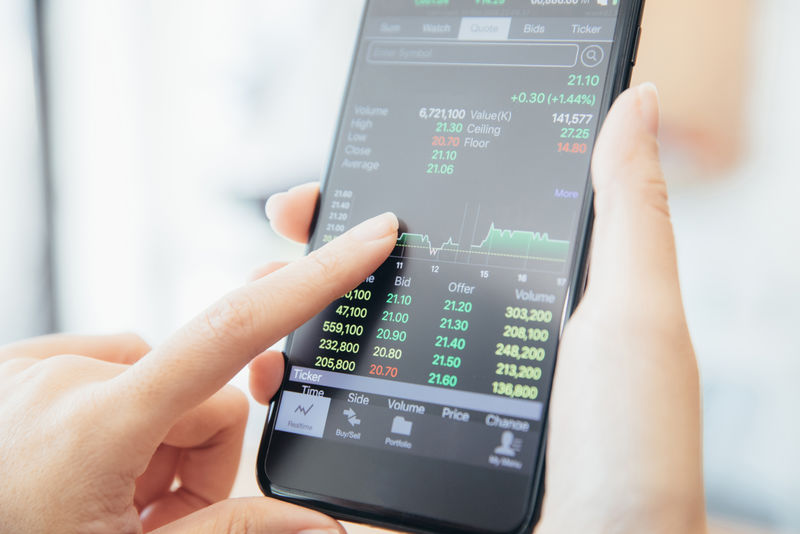 女性手拿着智能手机在咖啡店在线交易股票-商业理念