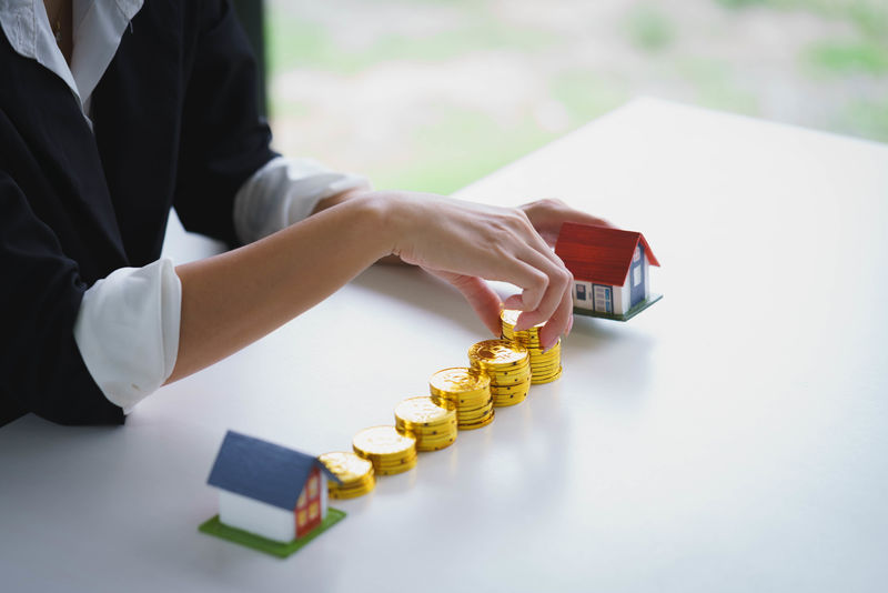 白色桌子上有木屋的钱币堆-为房地产节省资金-购买新房子和贷款-为将来的概念做准备