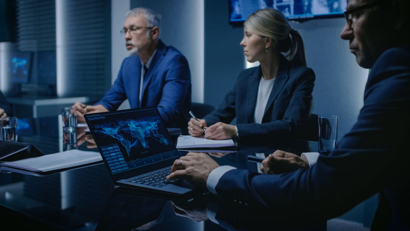 正在讨论紧急会议的政府机构官员-认真的人在会议室谈判-在后台屏幕中显示地图和数据流