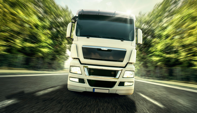 蓝天下公路上的白色卡车-特写镜头