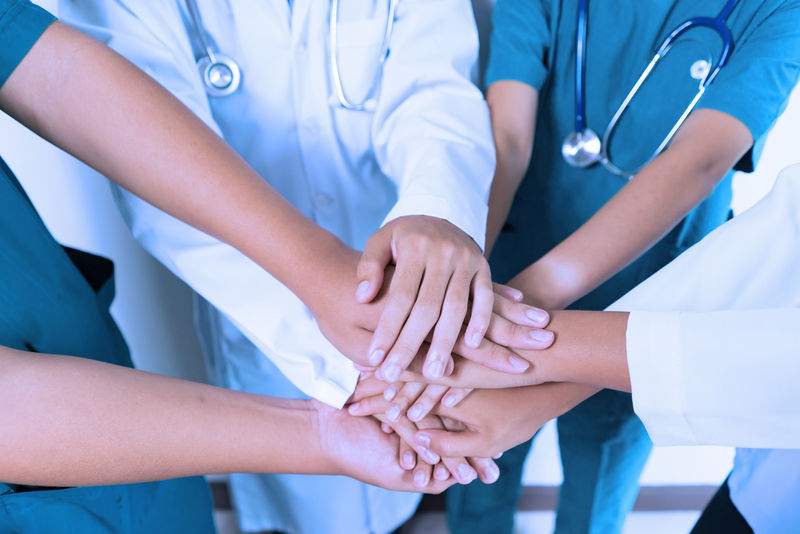 医生和护士协调医院的双手叠放,概念团队合作,快乐的医生作为团队协作