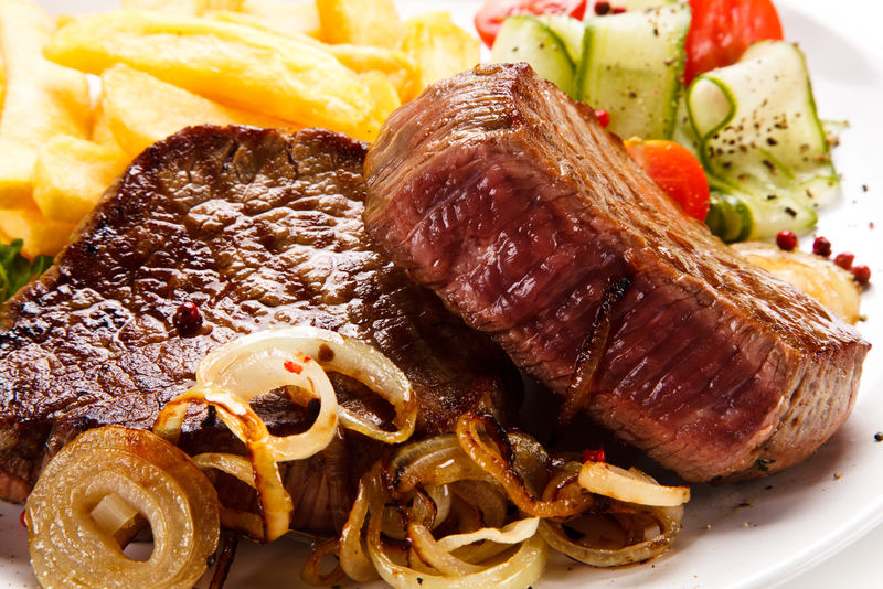 白底烤牛排配炸薯条和蔬菜沙拉