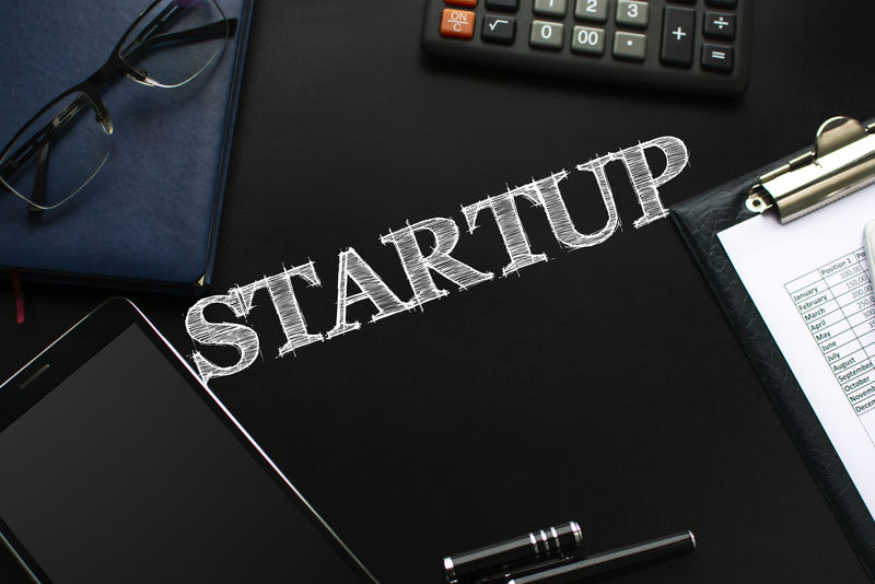 带商业配件的黑色黑板（记事本放大镜钢笔平板电脑电话眼镜和计算器）和文字启动-俯视图