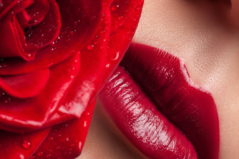 红唇在郁郁葱葱的玫瑰背景-嘴唇和花朵特写镜头