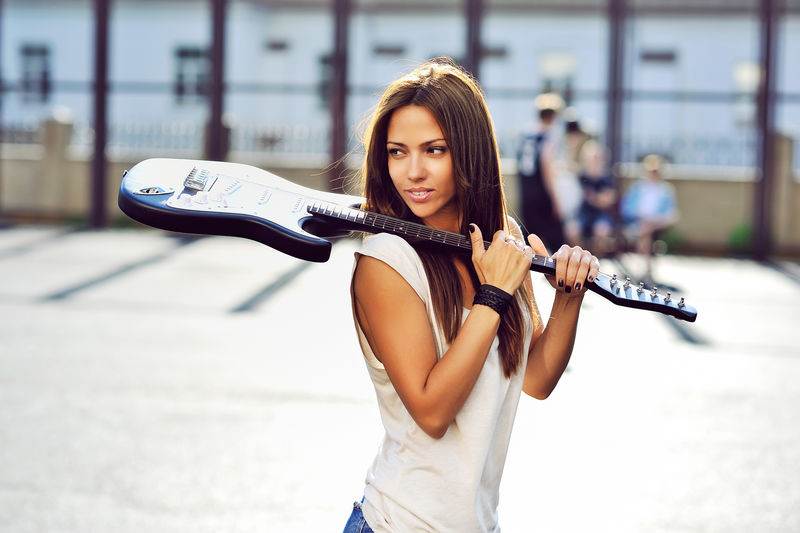 带吉他的迷人年轻女子-户外时尚肖像