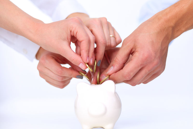 人们把硬币放进储蓄罐里