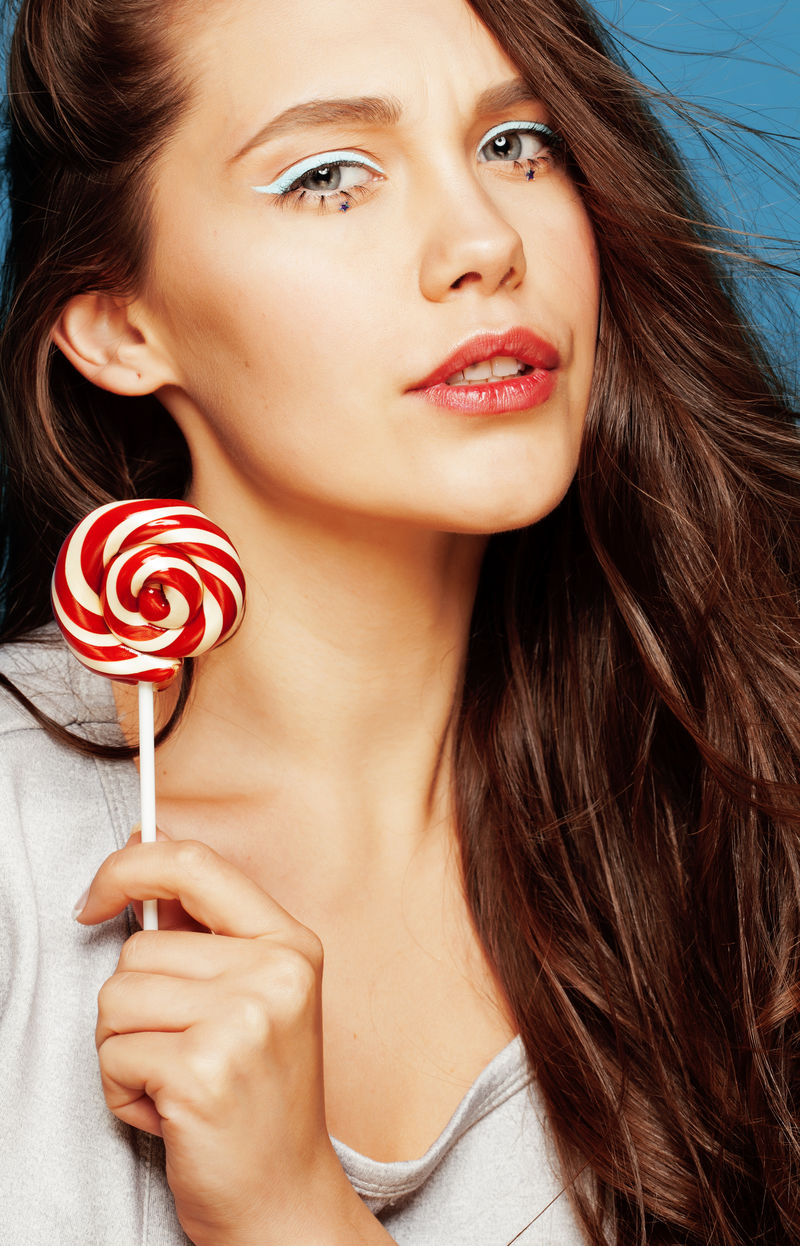 年轻可爱的女人糖果像娃娃一样贴近