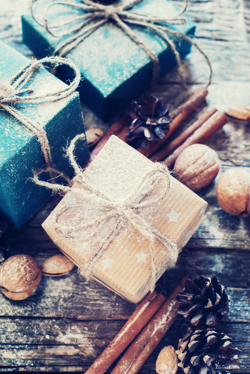 节日蓝色米色盒子与亚麻绳装饰的天然桂皮松果核桃色调图像