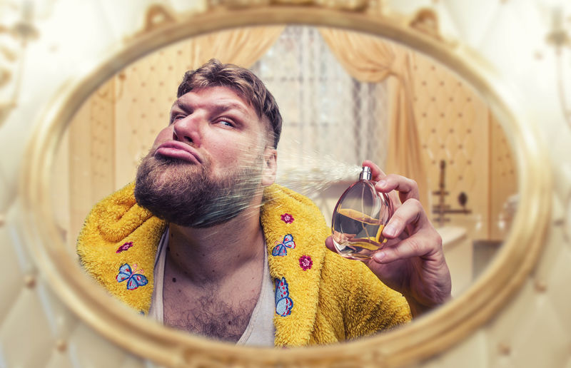 奇怪的人看着镜子散发着香味