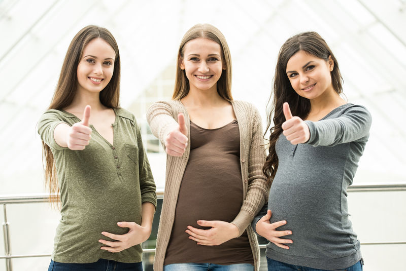 三位快乐孕妇的画像正在看相机