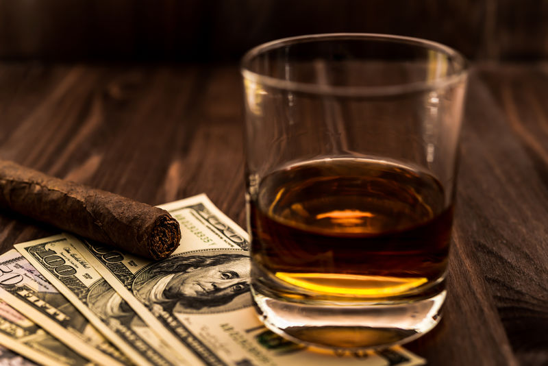 一杯威士忌酒和一张放在木桌上的古巴雪茄钱视角聚焦古巴雪茄