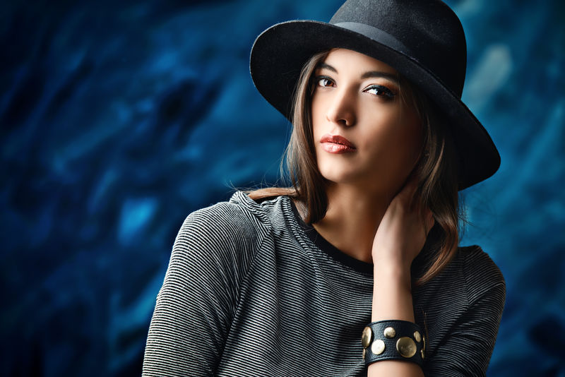 摄影棚拍摄了一位身着紧身连衣裙戴着优雅经典帽子的年轻女子美时尚概念