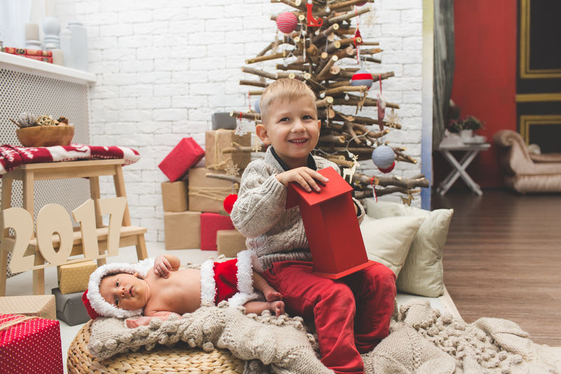 在时尚圣诞树旁微笑的男孩和他的弟弟