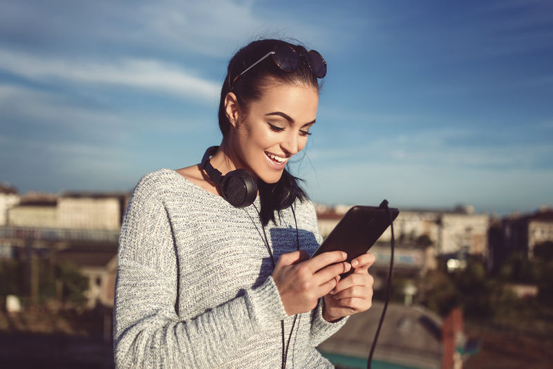 年轻时尚女性戴耳机和平板户外