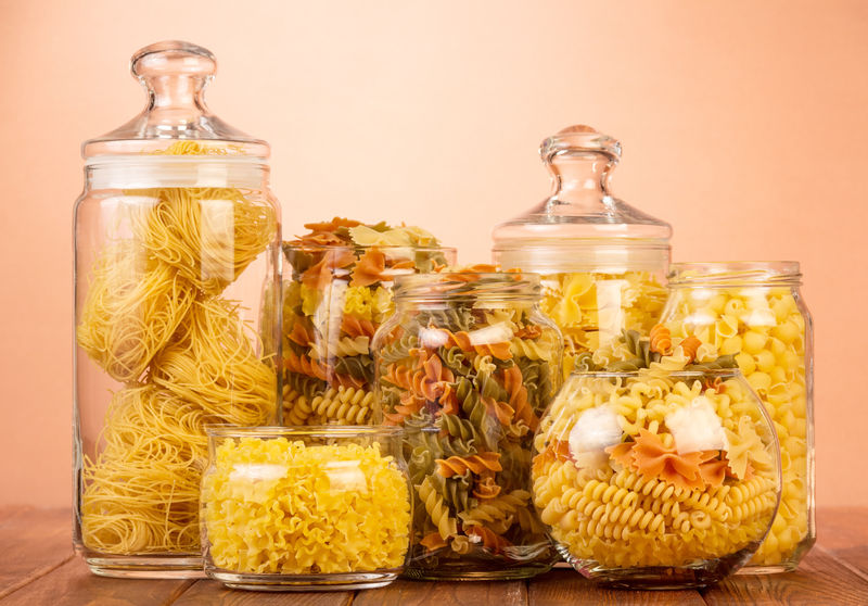 不同类型的生意大利面放在透明的银行里放在一个棕色的柜子上