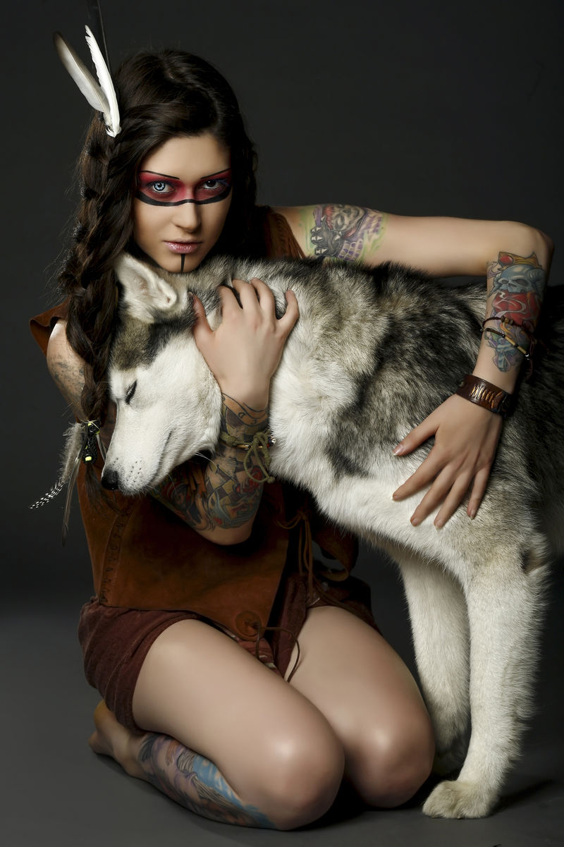 美丽的女人在美国本土服装摆在哈斯基狗的工作室